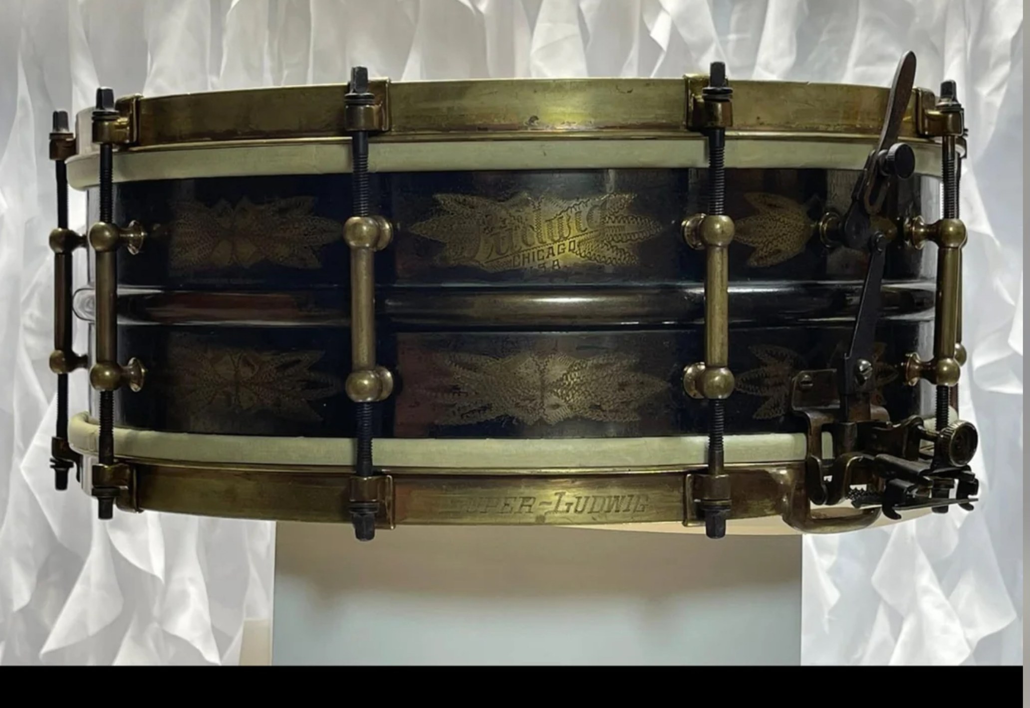 Restored vintage Ludwig De Luxe No. 231 snare drum with engraved black shell, gold floral engraving, and aged brass hoops