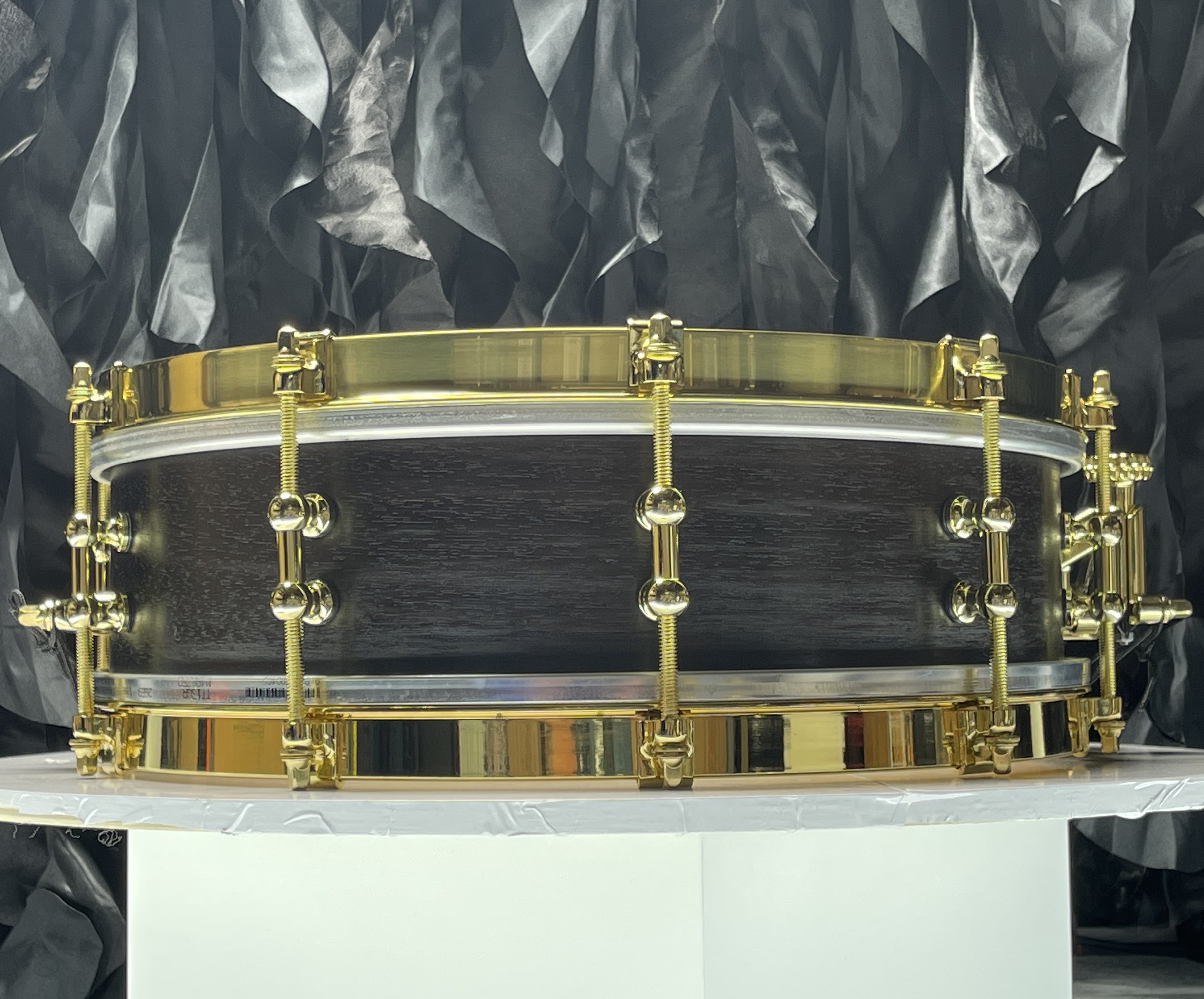 Back view of the restored 13x4 rosewood piccolo snare drum, brass hardware, on display stand